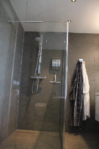 Badkamer in aanbouw met grootformaat wandtegels en ingebouwde nis.