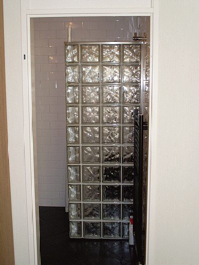 Doucheruimte met een wand van glazen bouwstenen en witte metrotegels.