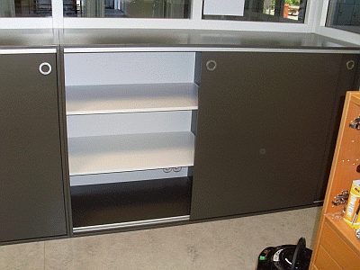 Op maat gemaakte kast met donkere schuifdeuren en witte legplanken.